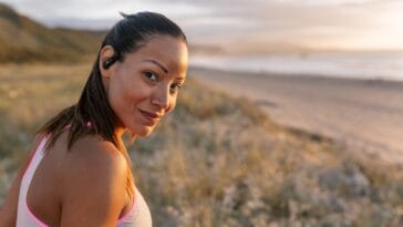 Portrait of a beautiful smiling woman on the beach at sunset. She looks directly into the camera